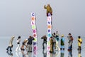 Group of Miniature diverse figurines people walking around a Group Of Letters forming Words Spelling