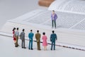 Group of miniature people holding a meeting