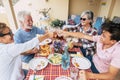 Group of mixed generations people have fun together during lunch at home in outdoor terrae - cheerful men and women from. old to