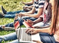 Group of mixed races teenagers using laptops and smartphones out
