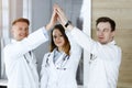 Group of modern doctors standing as a team while joining hands or giving five to each other. Physicians ready to examine Royalty Free Stock Photo