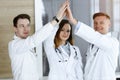 Group of modern doctors standing as a team while joining hands or giving five to each other. Physicians ready to examine Royalty Free Stock Photo