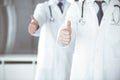 Group of modern doctors standing as a team with thumbs up or Ok sign in hospital office, close-up. Medical help