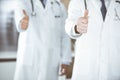 Group of modern doctors standing as a team with thumbs up or Ok sign in hospital office, close-up. Medical help