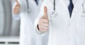 Group of modern doctors standing as a team with thumbs up or Ok sign in hospital office, close-up. Medical help