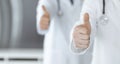 Group of modern doctors standing as a team with thumbs up or Ok sign in hospital office, close-up. Medical help