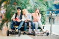 Group of people on electric scooter hoverboard sitting at bench and using phone Royalty Free Stock Photo