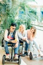 Group of people on electric scooter hoverboard sitting at bench and using phone Royalty Free Stock Photo