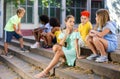Positive tweenagers friendly blabbing while sitting on steps outdoors