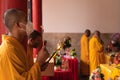 A Group of monks holding Buddist music instruments while praying together