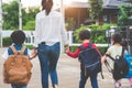 Group of mother and kids holding hands going to school with schoolbag. Mom bring children walk to school by bus together with sat Royalty Free Stock Photo