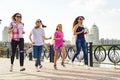 Group of mothers and daughters are running along the road in the park.