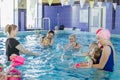 Group of mothers with little babies in children`s swimming section with coach. Healthy lifestyle