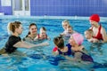Group of mothers with little babies in children`s swimming section with coach. Healthy lifestyle