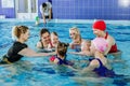 Group of mothers with little babies in children`s swimming section with coach. Healthy lifestyle