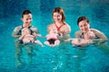 A group of mothers with their young children in a children`s swimming class with a coach.