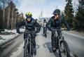 Group of mountain bikers riding on road outdoors in winter. Royalty Free Stock Photo