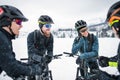 Group of mountain bikers standing on road outdoors in winter, talking. Royalty Free Stock Photo