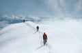 A group of mountaineers climbs to the top of a snow-capped mountain. Climbers are hiking on mountain peaks ridge