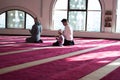 Group of muliethnic religious muslim young people praying an dreading Koran together. Group of muslims praying in the mosque