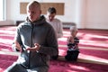 Group of muliethnic religious muslim young people praying an dreading Koran together. Group of muslims praying in the mosque