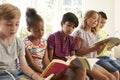 Group Of Multi-Cultural Children Reading On Window Seat Royalty Free Stock Photo