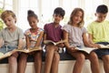 Group Of Multi-Cultural Children Reading On Window Seat Royalty Free Stock Photo