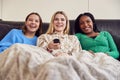 Group Of Multi-Cultural Teenage Girl Friends Snuggled Under Blanket Watching TV At Home Royalty Free Stock Photo