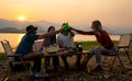 Group of multi-ethnic friends men and women sit on chair with party and camping together also cheers with bottle near lake in