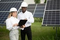 Group of multi ethnic people and safety helmets staring at solar farm. Royalty Free Stock Photo