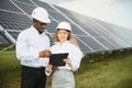 Group of multi ethnic people and safety helmets staring at solar farm. Royalty Free Stock Photo