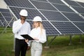 Group of multi ethnic people and safety helmets staring at solar farm. Royalty Free Stock Photo