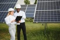 Group of multi ethnic people and safety helmets staring at solar farm. Royalty Free Stock Photo
