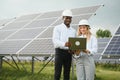 Group of multi ethnic people and safety helmets staring at solar farm. Royalty Free Stock Photo