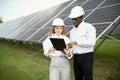 Group of multi ethnic people and safety helmets staring at solar farm. Royalty Free Stock Photo