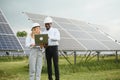 Group of multi ethnic people and safety helmets staring at solar farm. Royalty Free Stock Photo