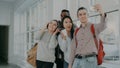 Group of multi-ethnic students taking selfie on smartphone camera while standing in corridor of university . Hipster guy Royalty Free Stock Photo