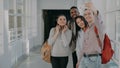 Group of multi-ethnic students taking selfie on smartphone camera while standing in corridor of university . Hipster guy Royalty Free Stock Photo