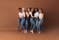 Group of multi-ethnic women in casuals posing together against a brown background Royalty Free Stock Photo