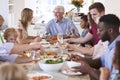 Group Of Multi-Generation Family And Friends Sitting Around Table And Enjoying Meal Royalty Free Stock Photo