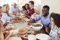 Group Of Multi-Generation Family And Friends Sitting Around Table And Enjoying Meal Royalty Free Stock Photo