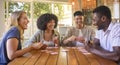 Group Of Multi-Racial Friends Sitting Around Table Playing Game Of Cards At Home Together Royalty Free Stock Photo