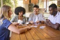 Group Of Multi-Racial Friends Sitting Around Table Playing Game Of Cards At Home Together Royalty Free Stock Photo