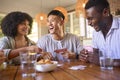 Group Of Multi-Racial Friends Sitting Around Table Playing Game Of Cards At Home Together Royalty Free Stock Photo