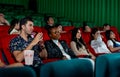 Group of multiethic people sit on seats in cinema theater and they look boring during watch movie and someone sleep in the hall Royalty Free Stock Photo