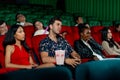 Group of multiethic people sit on seats in cinema theater and they look boring during watch movie and someone sleep in the hall Royalty Free Stock Photo
