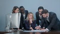 Group of multiethnic diverse young business people in a meeting standing around a table with serious expressions Royalty Free Stock Photo