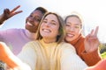 Group of multiethnic smiling friends taking a selfie outdoors, students college campus life