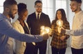 Team of diverse business people standing in circle and holding shining light bulbs Royalty Free Stock Photo