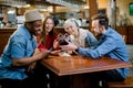 Group of multiracial friends enjoying in cafe together. Young people meeting in a cafe. Young men and women sitting at Royalty Free Stock Photo